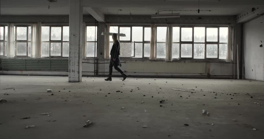 A woman walking through an abandoned warehouse