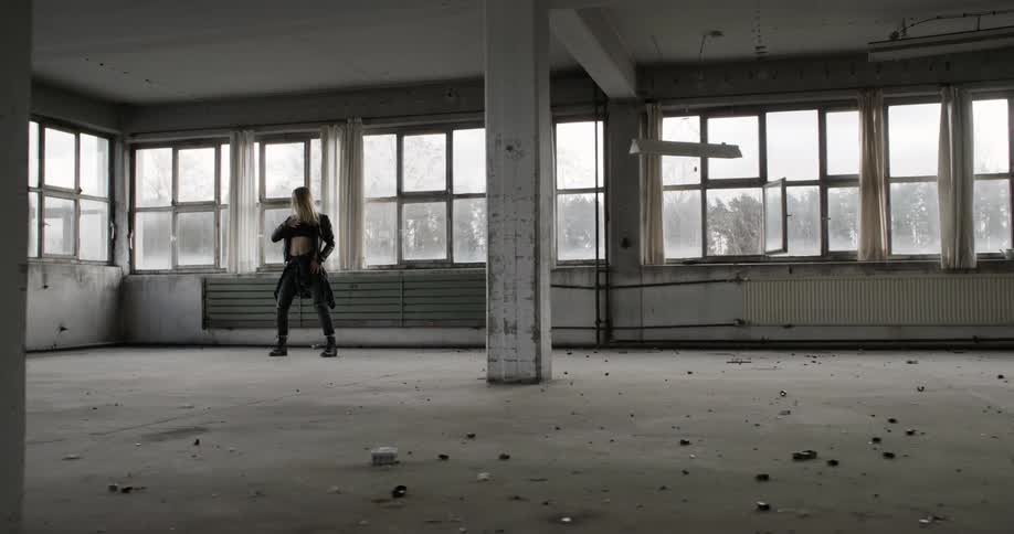 A woman dances in a dirty warehouse