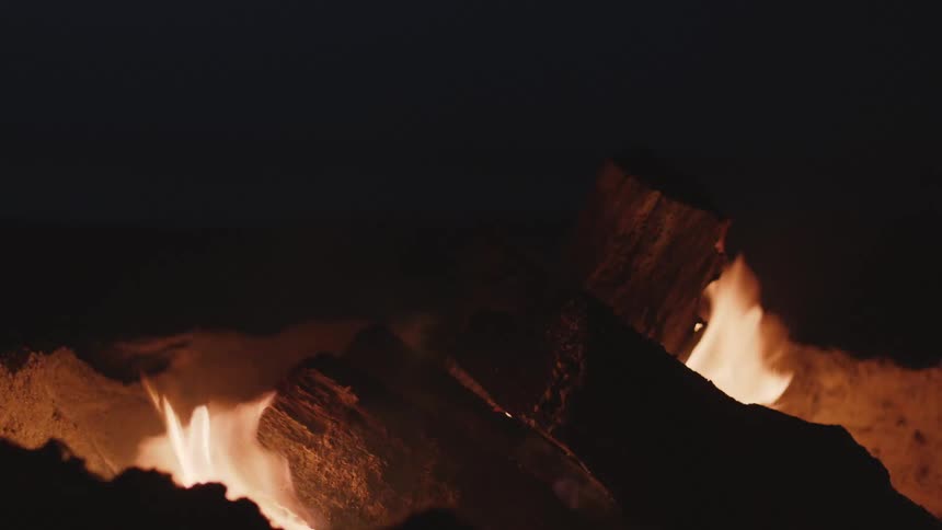 Flames and sparks rise from a burning camp fire
