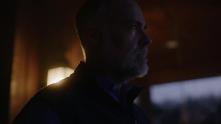 A man stands on his porch with a cup of coffee and looks in to the distance
