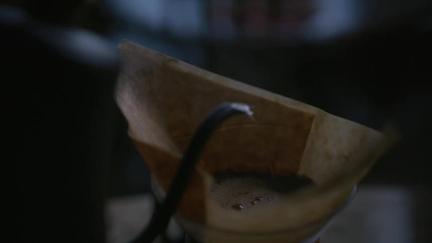 Boiled water is poured from a kettle into a pour over coffee carafe