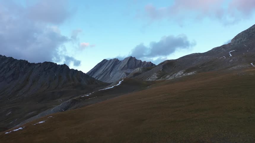 A mountain ridge over a hill and under a cloudy sky
