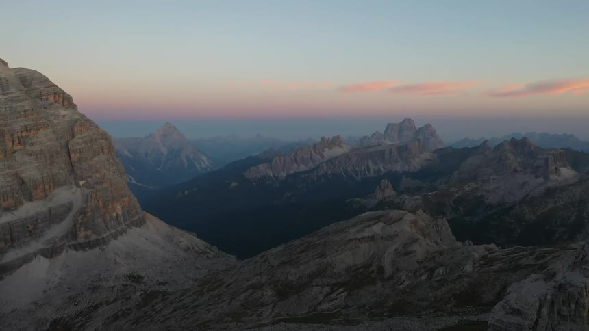 Rock formations and mountains in the distance with a few clouds in the sky in the Italian Dolomites