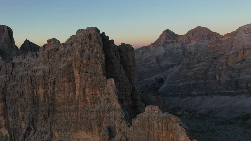 Rock formations peak high in a clear sky and mountains in the distance in the Italian Dolomites