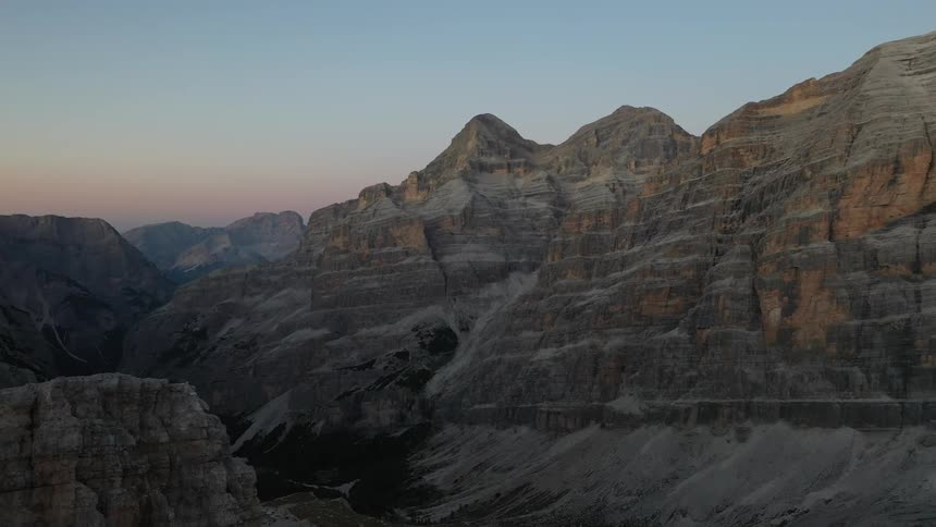 Rock formations peak high in a clear sky and there are mountains in the distance