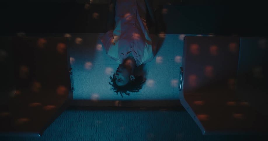A teenage boy lies under strobing lights
