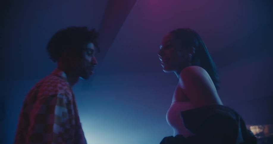 Woman and man dancing in an empty bowling alley with a spotlight in the background