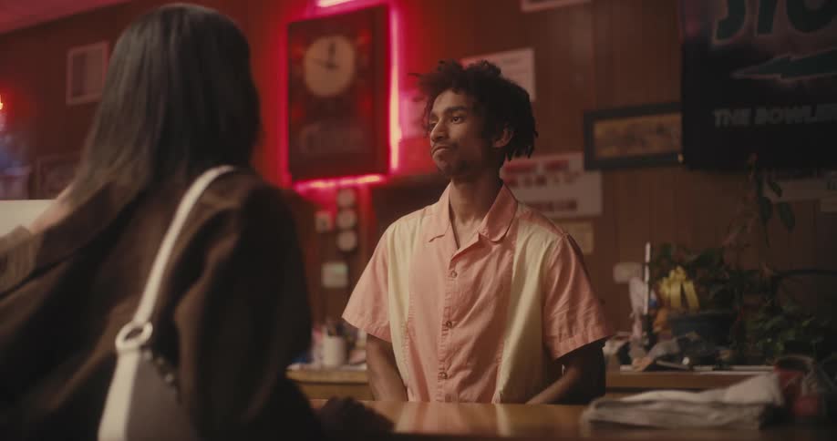 A customer standing at a counter taps her fingers to get the employee to look at her