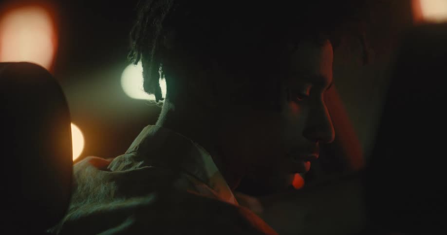 A man sitting in a car at night leans over and kisses the woman next to him