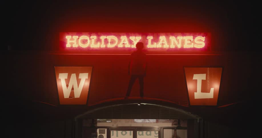 A man dances on the awning to the entrance of a bowling alley