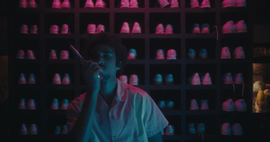 A bowling alley employee sings into a microphone while standing in front of shelves and bowling shoes