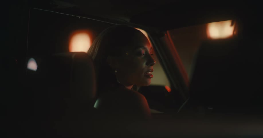 Young woman entering a car in the passenger seat and kissing the man who is in the drivers seat