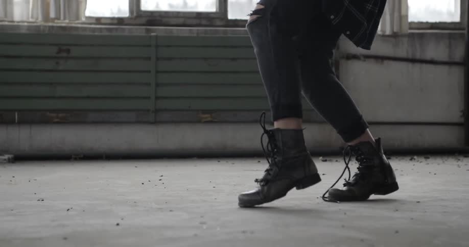 A young, blonde woman practicing dance moves in an abandoned building