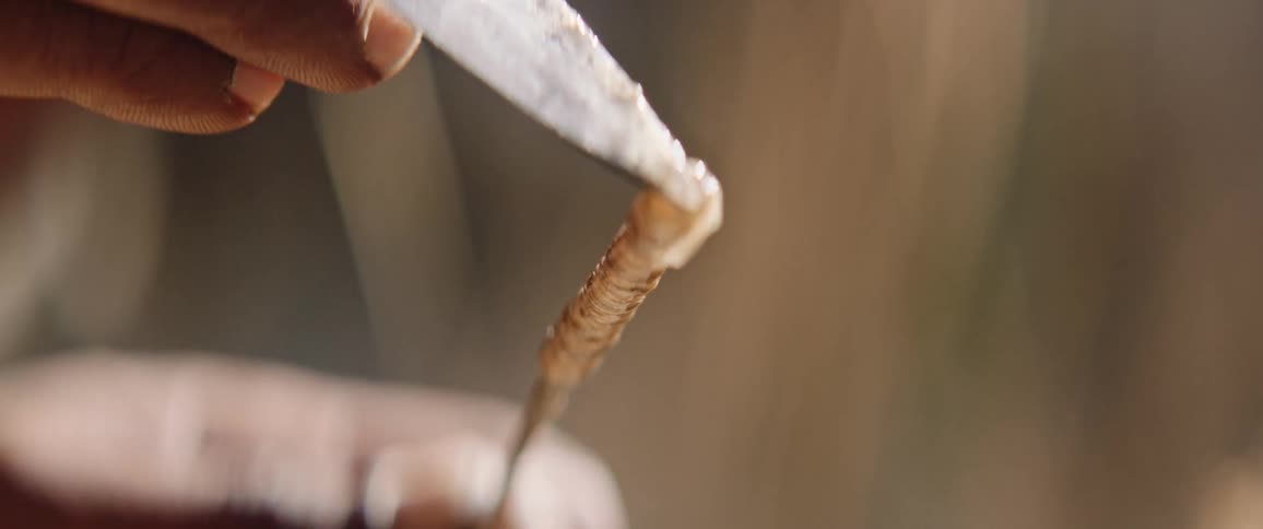 Indigenous men making arrow for hunt