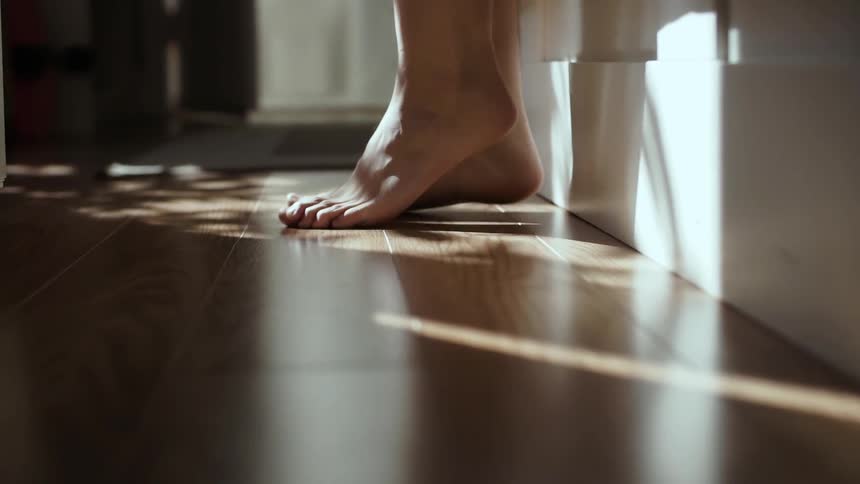 Person puts their feet on the ground from bed