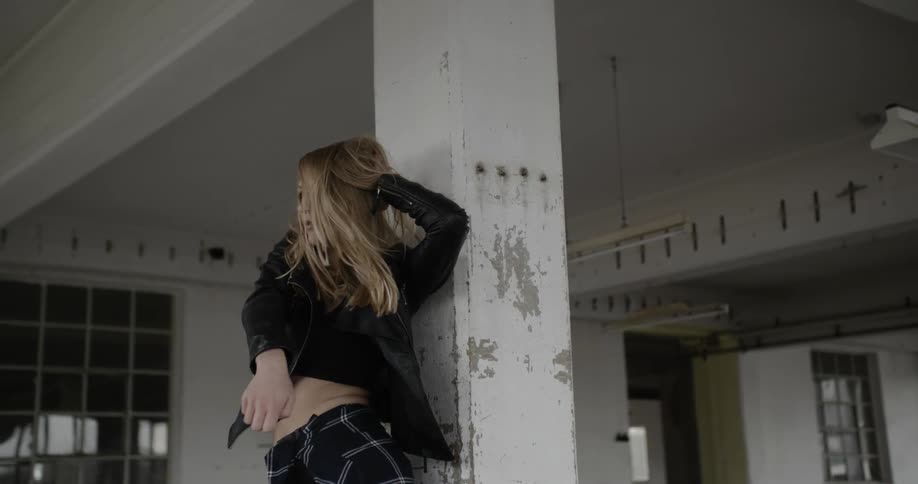 A woman dances near a chipped pillar
