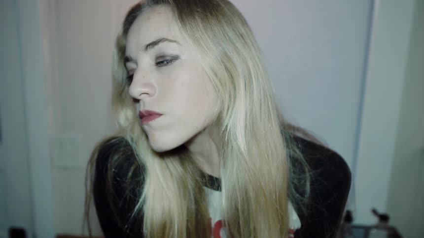 Blonde woman shaking her head before looking into the lens