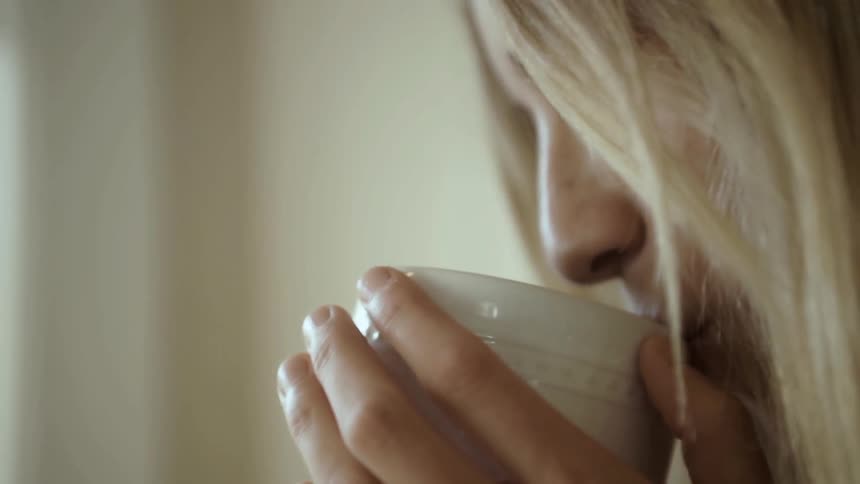 Woman laughs and sips from a white mug