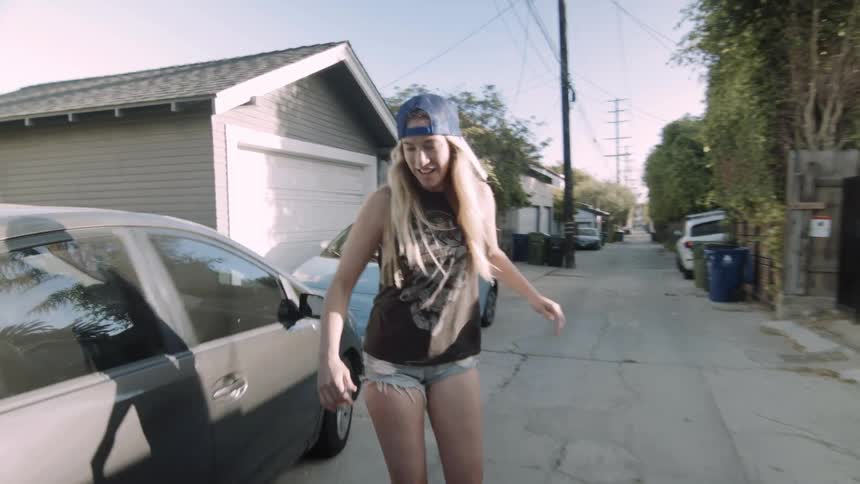 A young lady rides a skateboard down an alley