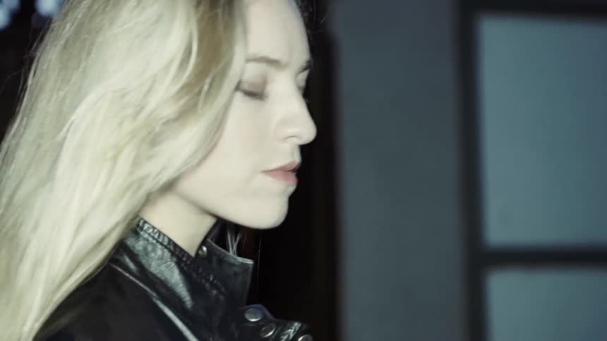 A blonde woman walks in front of a building