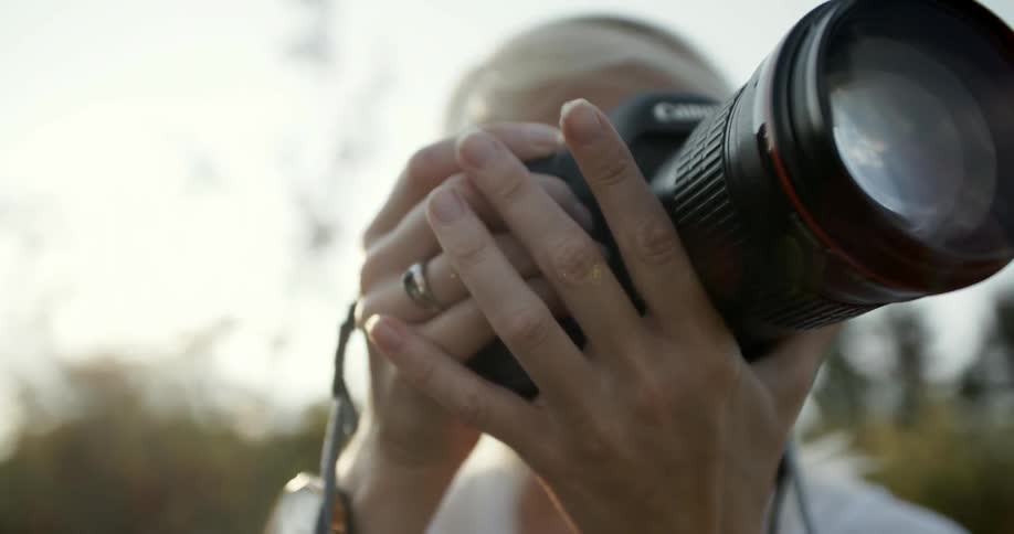 A woman points a camera with a long lens