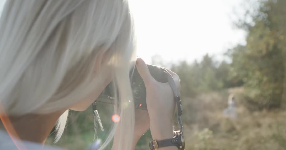 Blonde woman taking pictures in nature at sunset