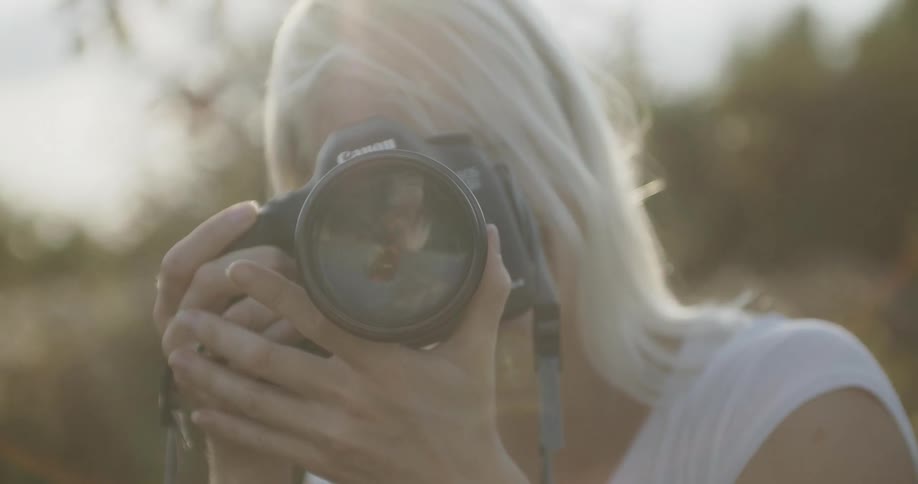 A blonde woman takes a picture with a camera