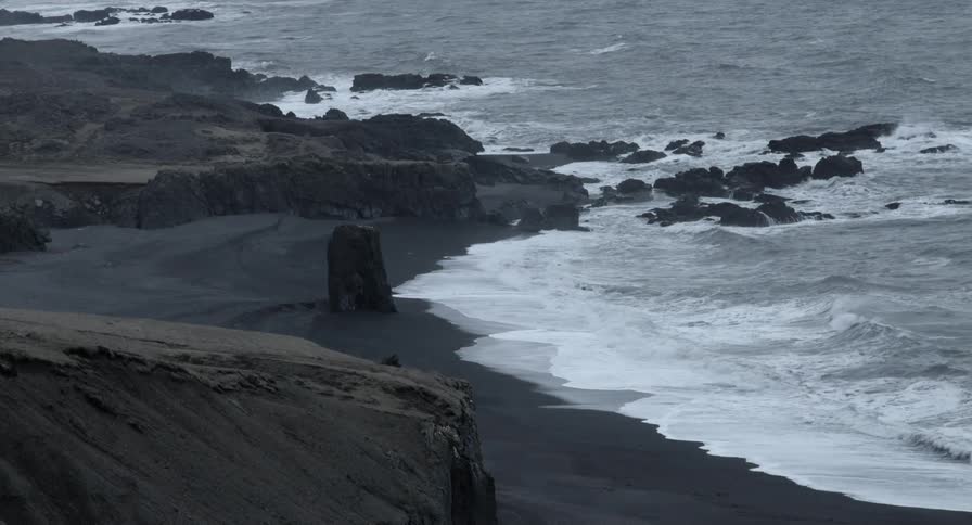 Waves coming ashore on a rocky dark beach