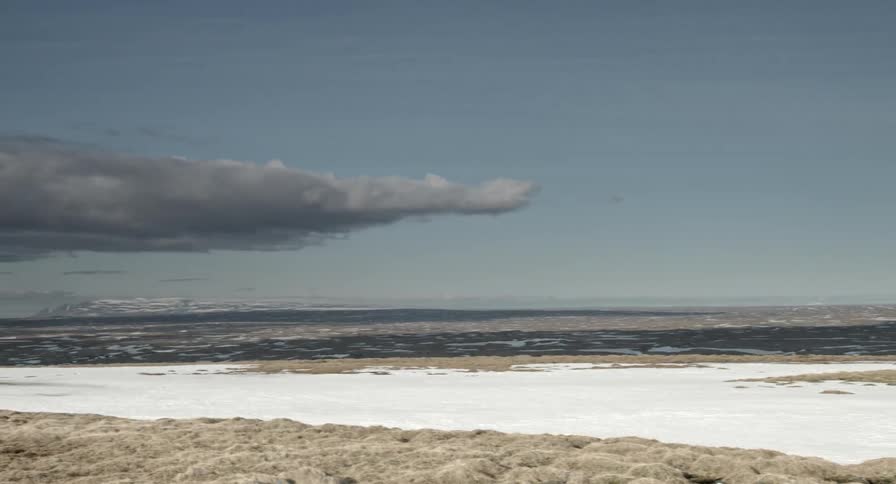 Desolate flat land partially covered in snow