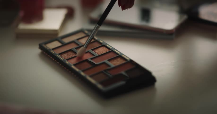 A person dips their brush in the makeup