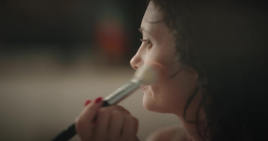 Woman smiles and talks as she applies blush to her cheeks