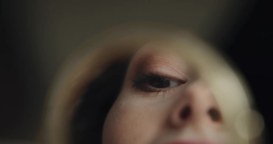A woman uses a mirror to see her mouth while lining her lips