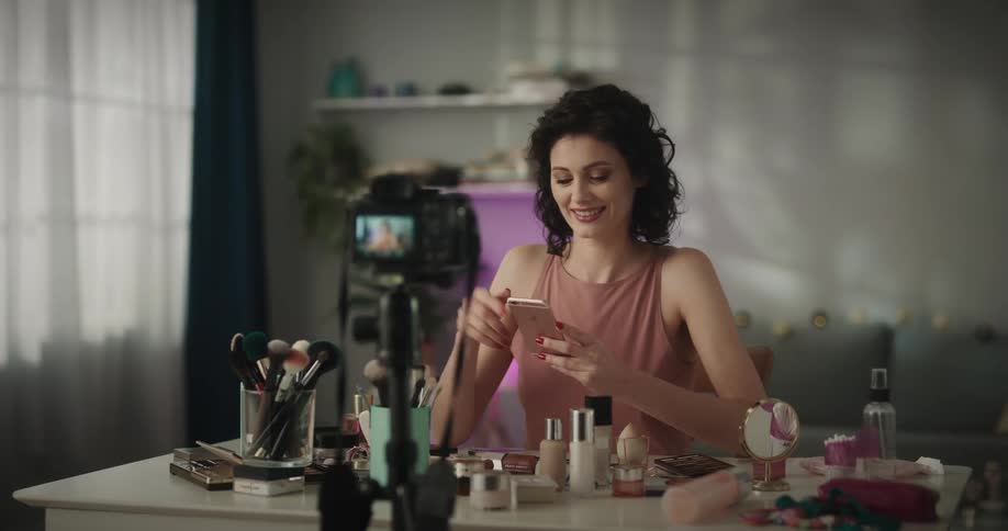 A woman scrolls through her feed smiling and shaking her head as she films herself