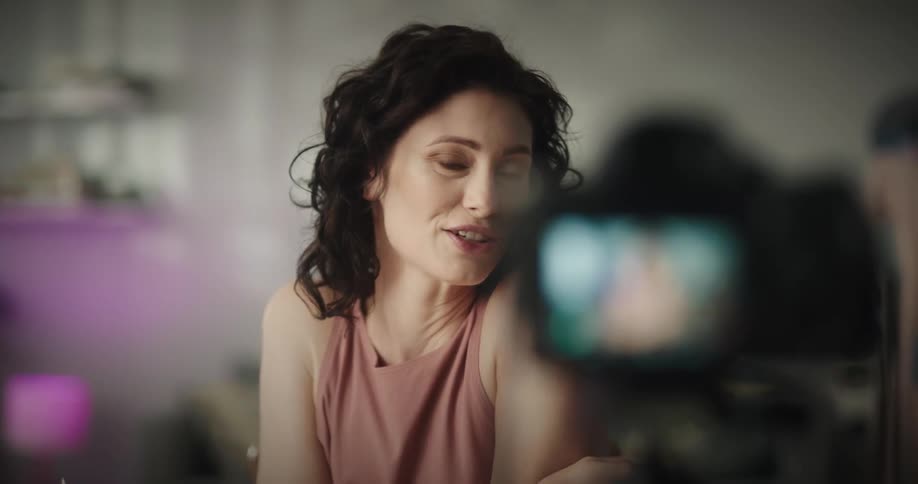 Camera records a woman that is smiling and demonstrating how to use a makeup pencil
