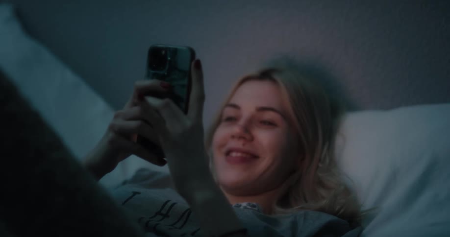 A view of a woman smiling while looking at a phone