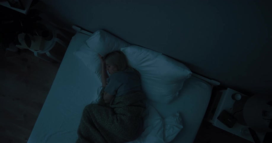 An overhead view of a woman sleeping in her bed at night