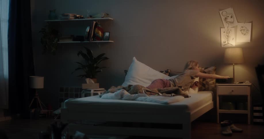 Blonde woman turns off light and goes to sleep in bedroom