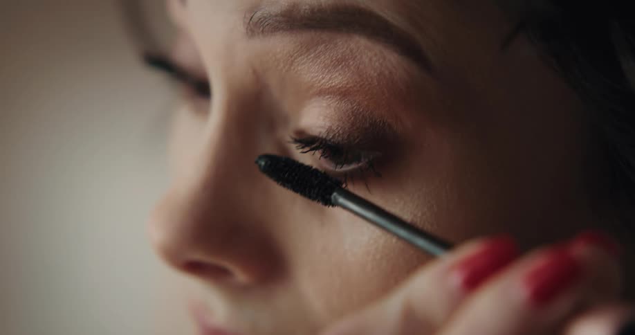 White woman applying mascara on eyelashes