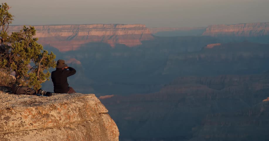 A person is sitting on a ledge of a cliff