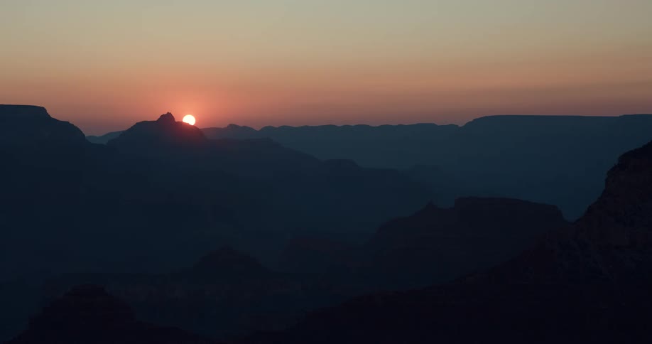 The sun glows brightly as it rises over a ridge on the horizon