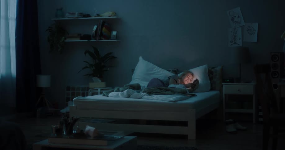 A woman laying in a bed using a smartphone