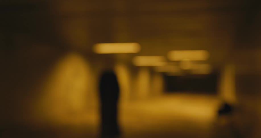 A woman looks back anxiously as she takes her drug buy and walks down the tunnel