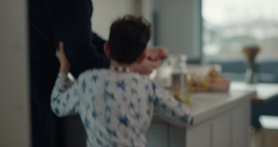 A boy hands eggs to his father in the kitchen