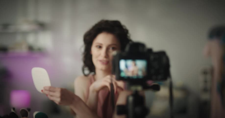 White woman applying makeup and talking to the camera while recording herself in a photography camera