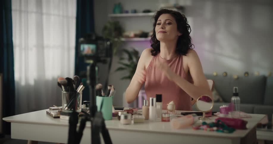 A woman makes a heart with her hands and blows kisses to her audience before turning off the camera