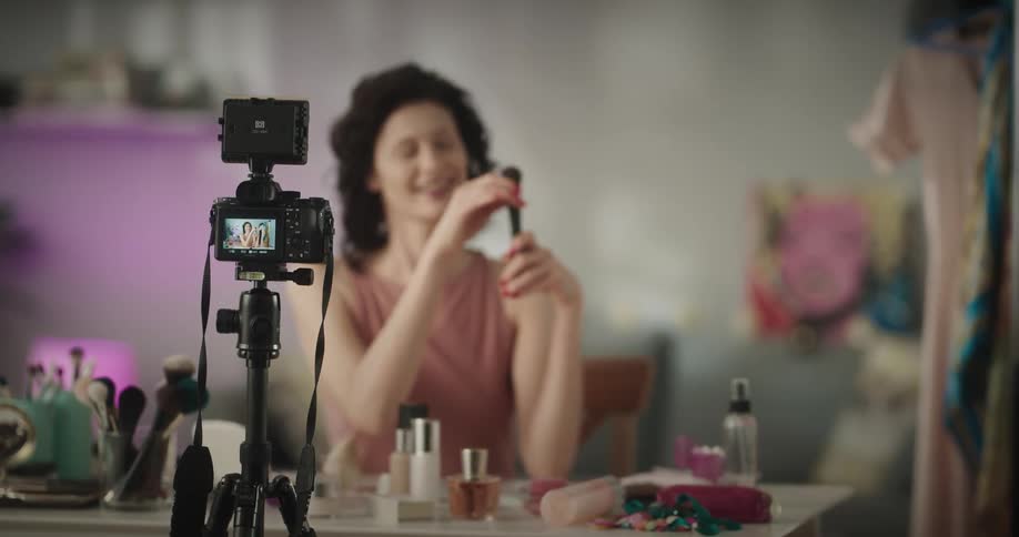 A woman holds a makeup brush and demonstrates how to use it while filming herself