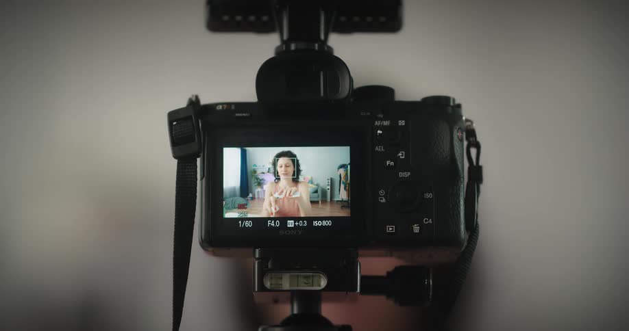 A woman records herself applying lotion to her face