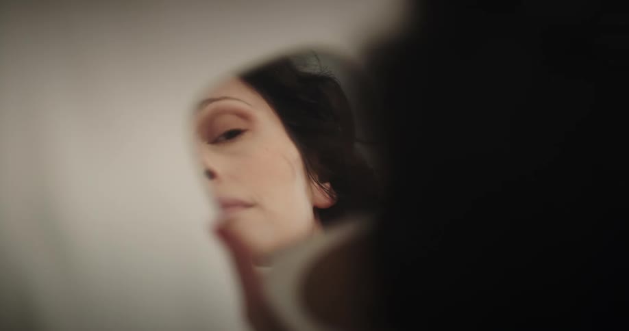 Woman holding hand mirror puts on makeup
