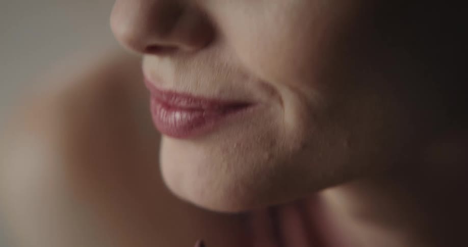 Woman applies lipstick to her lips with a lipstick pencil and smiles