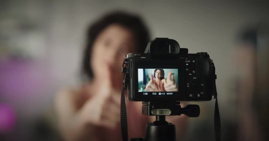 White woman sitting in a room recording a video about makeups on her photography camera